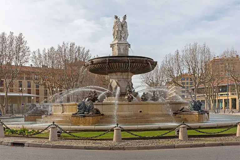 Fontaine monumentale sur une place ensoleillée.