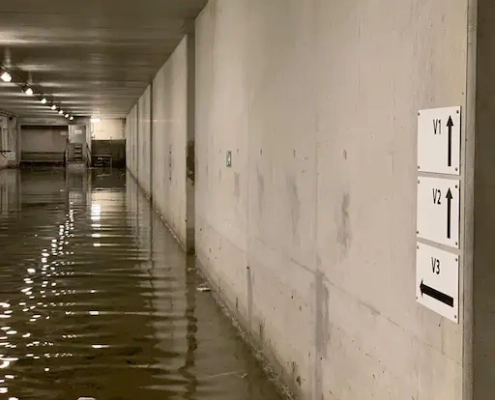 Parking souterrain inondé avec panneaux de direction.