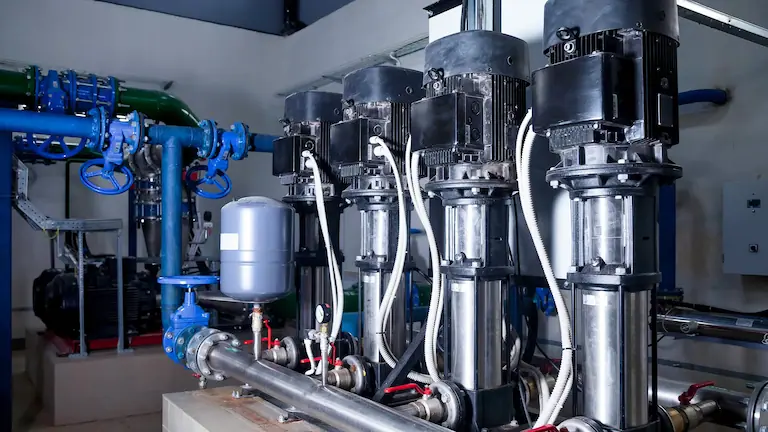 Salle de pompage industrielle avec tuyaux et vannes.
