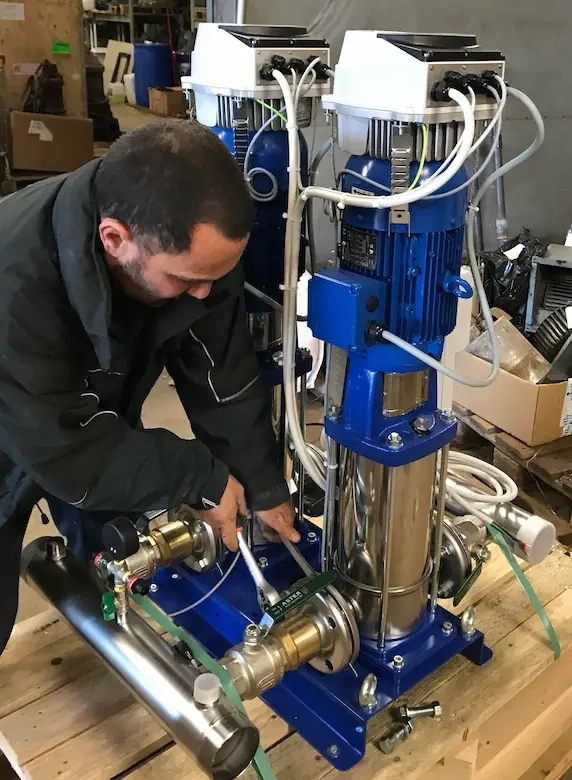 Technicien répare une pompe industrielle bleue.