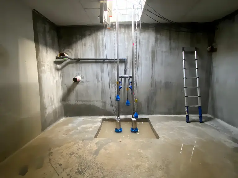 Salle technique avec tuyaux et échelle.